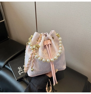 Détail de broderie florale sur sac seau rose avec poignée en perles et bandoulière