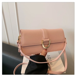 Détail d'un sac bandoulière en cuir rose avec une boucle en D en métal doré poli