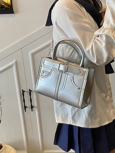 Sac à main argenté métallisé avec double poignée et bandoulière porté par mannequin