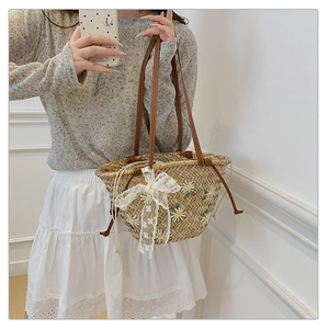 Detail of straw bucket bag with white daisy embroidery and lace bow for summer beach style