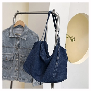 Detail view of a large navy denim tote bag with silver eyelets and soft twill texture