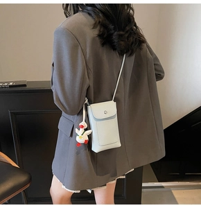 Detail of light blue textured phone crossbody bag with a cute plush duck charm on the side