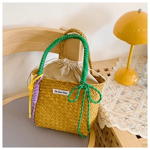 Detail of hand-woven straw bucket bag with green rope handle and internal drawstring pouch