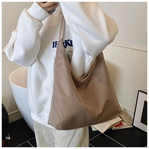 Close-up of earth-toned waterproof nylon tote bag styled with casual white sweatshirt