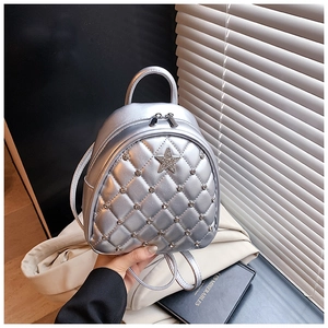 Macro detail of silver quilted mini backpack with sparkling rhinestones and star emblem