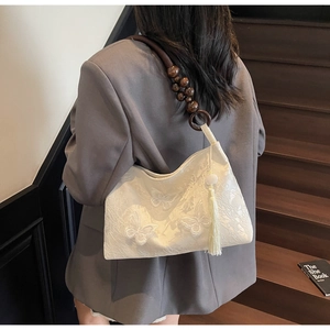 Détail de la broderie papillon blanche et de la sangle en perles de bois du sac