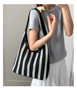 Close-up of black and white striped woven tote bag with wide leather shoulder strap