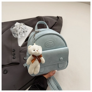 Close-up of light blue textured leather mini backpack with cute teddy bear charm