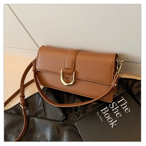 Détail d'un sac à main en cuir marron caramel avec boucle dorée en forme de D