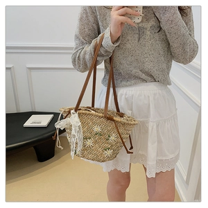 Close-up of handmade straw bucket bag featuring daisy embroidery and a white lace bow