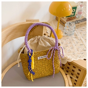 Close-up of handmade straw bucket bag with purple rope handles and drawstring liner
