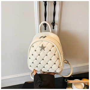 Detail of white quilted mini backpack featuring silver studs and a star emblem