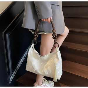 Détail du sac cabas en dentelle blanche avec broderie papillon et anse en perles de bois