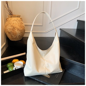 Close-up of a cream-colored large tote bag displayed in a minimalist artistic setting