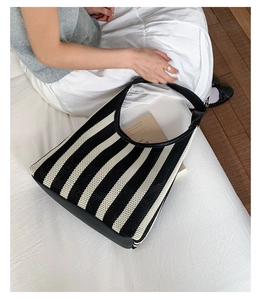 Detail of black and white vertical striped woven tote bag with premium leather handles