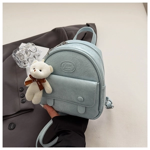 Detail of light blue mini backpack with wrinkled texture and cute white plush bear pendant