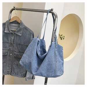 Detail of blue denim tote bag with metallic eyelets hanging on a minimalist hanger