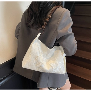 Détail du sac cabas blanc à papillons avec texture florale et bandoulière en perles