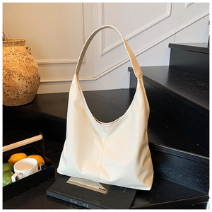 Close-up of cream-colored large Hobo bag with middle seam detail on dark wood background