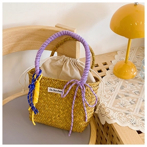 Detail of hand-woven straw bucket bag featuring colorful rope handle and inner drawstring
