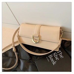 Détail du sac à bandoulière beige avec boucle fer à cheval dorée sur fond de cuir noir