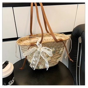 Detail of straw bucket bag featuring daisy embroidery and a white lace bow accent
