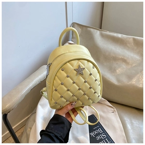Close-up of yellow quilted leather mini backpack with star studs and round rivets decoration