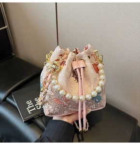 Détail du sac seau brodé rose avec poignée en perles et motifs de grue