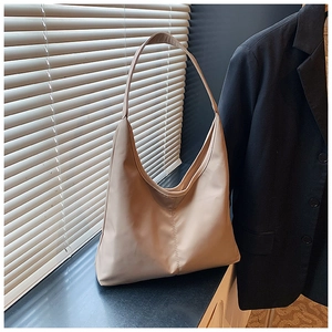 Detail of minimalist beige hobo bag with wide handle on a professional workplace background