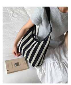 Detail of a minimalist black and white striped knit shoulder bag with leather trim and strap