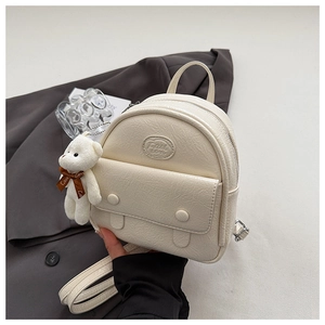 Detail of cream mini backpack featuring crinkled texture and cute plush bear charm
