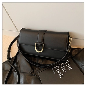Détail d'un sac à bandoulière noir rectangulaire avec boucle en D dorée sur cuir