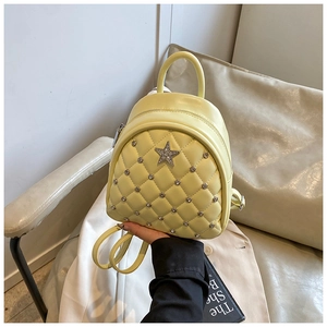 Detail of yellow mini quilted backpack with sparkling rhinestone stars and round studs