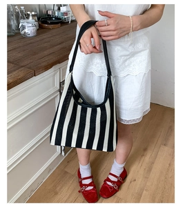 Detail of a black and white striped woven tote bag with premium leather straps