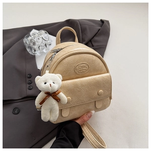 Close-up of beige wrinkled texture leather mini backpack with cute plush bear charm