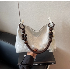 Détail du sac cabas blanc avec broderie florale et poignée en perles de bois avec pompon