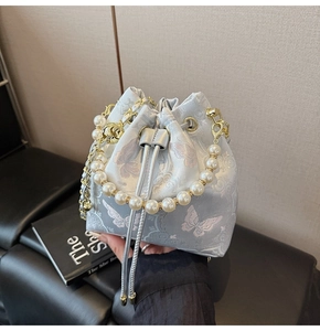 Vue détaillée du sac seau bleu clair brodé avec motifs papillons et poignée en perles