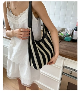 Detail of black and white striped knit tote bag with leather shoulder strap