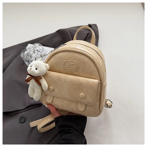 Detail of beige vintage mini backpack with pleated texture and plush bear charm decoration
