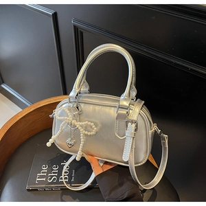 Detailed shot of silver faux leather pillow bag with pearl bow and heart charm