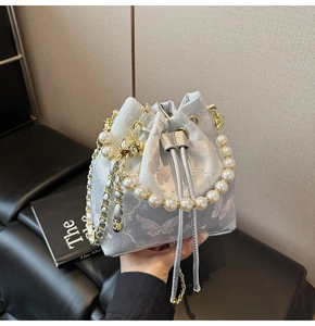 Broderie détaillée de papillons violets sur un sac seau en satin bleu clair aux perles