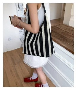 Detail of black and white striped mesh tote bag with wide shoulder strap on model