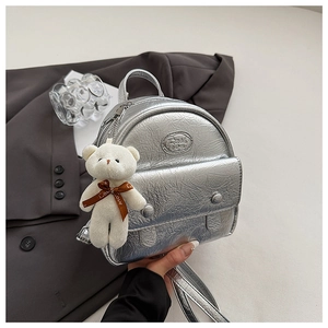 Detail of silver metallic crinkled mini backpack with white plush bear charm and logo