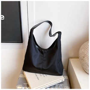 Detail of a large black hobo shoulder bag with wide strap on a minimalist studio setup