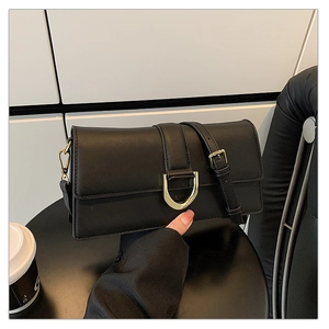 Détail d'un sac bandoulière en cuir noir avec boucle en D dorée et bandoulière réglable