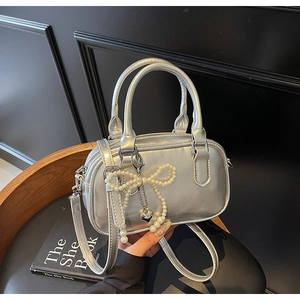 Detailed shot of silver oil wax leather pillow bag with pearl bow and heart charm