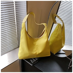 Detail of bright yellow hobo bag in smooth nylon texture on a dark wooden table