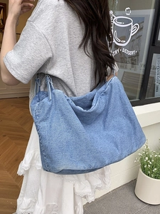 Light blue denim tote bag with large capacity, worn by model in an outdoor city setting