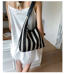Detail of a black and white striped knit tote bag showing spacious design and leather strap