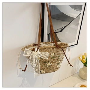 Detail of straw bucket bag with white daisy embroidery and a large lace bow accent